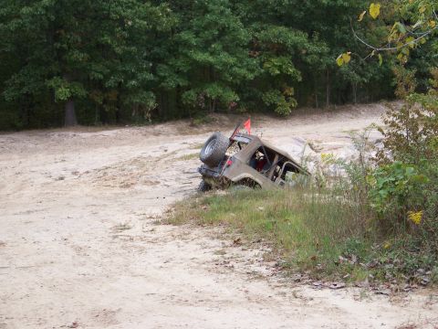 1989 Ford Bronco - An off-road vehicle is stuck in the mud on a dirt path with trees in the background.