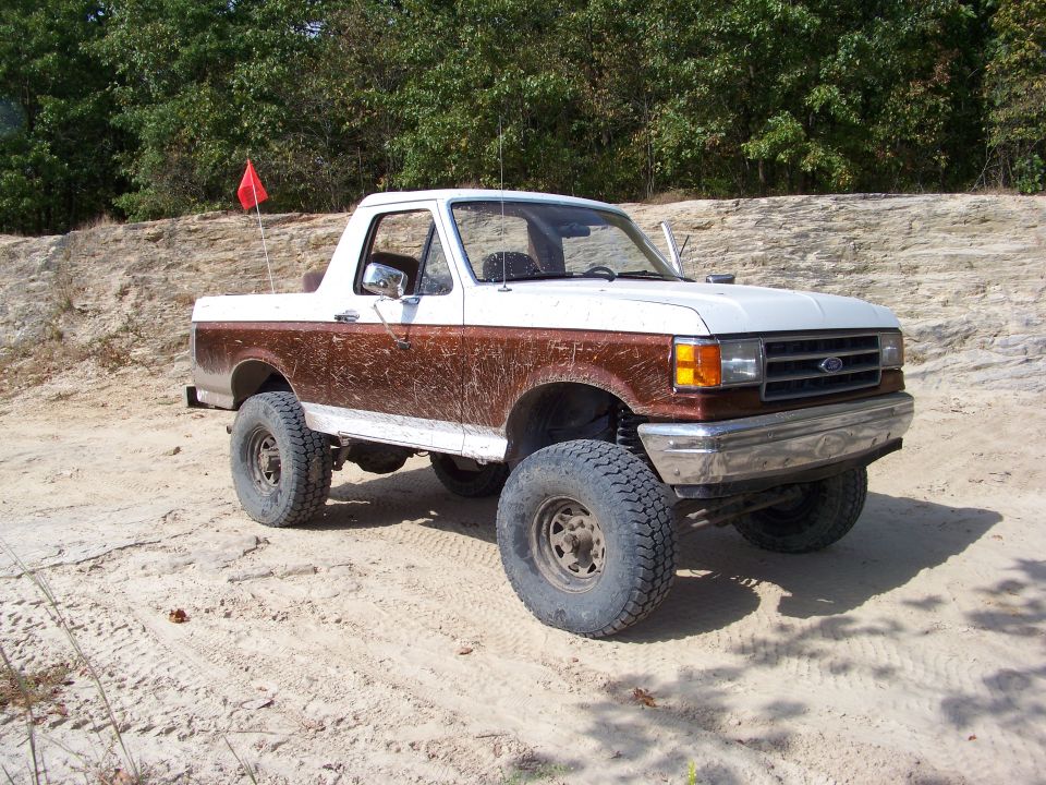 1989 Ford Bronco lifted with off-road tires and woodgrain trim parked on dirt
