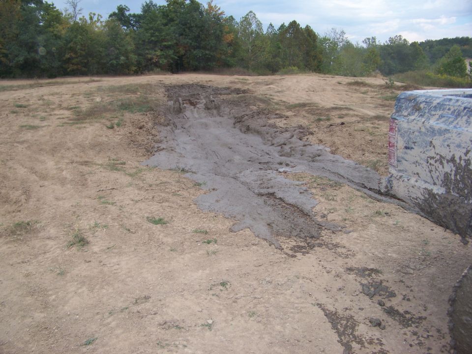 Muddy tire and fender of a blue vehicle on a dirt track