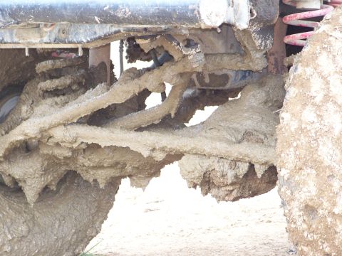 1989 Ford Bronco - The undercarriage of a vehicle is heavily coated in mud after off-roading.