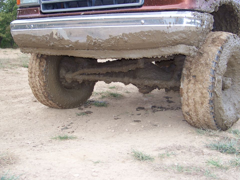 Mud-covered front axle and tires of a vehicle