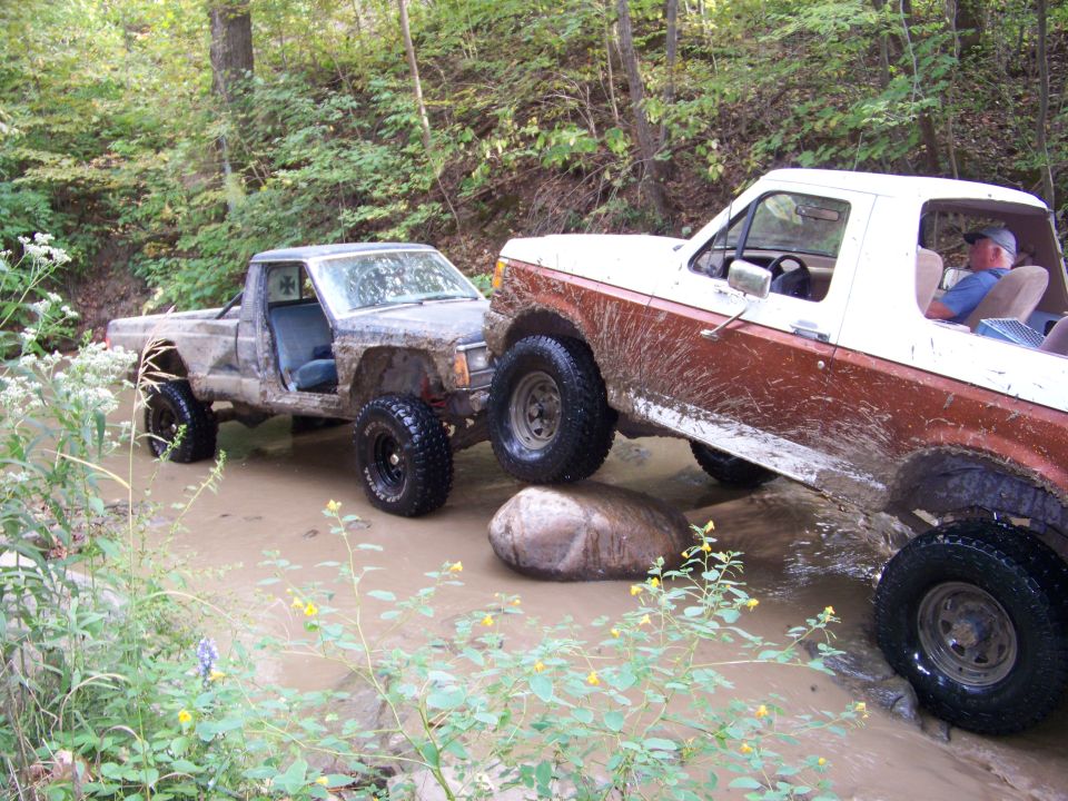 Ford Bronco and a Jeep Comanche driving through water