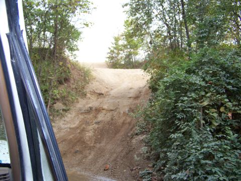1989 Ford Bronco - Driving up a steep, rutted dirt trail through trees. The view is from the driver's side.