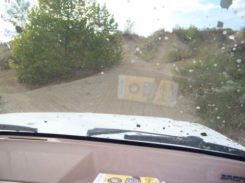 1989 Ford Bronco - Two cigarette packs lie on a dirt road, seen through a dusty windshield.