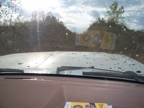 1989 Ford Bronco - Driving through a muddy, off-road terrain with a clear sky overhead.