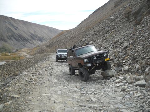 1986 Ford Bronco II - Two SUVs navigate a challenging, rocky mountain pass, demonstrating off-road capability.