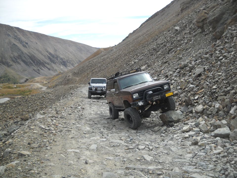 1986 Ford Bronco II and a Jeep Wrangler on a steep, rocky mountain trail