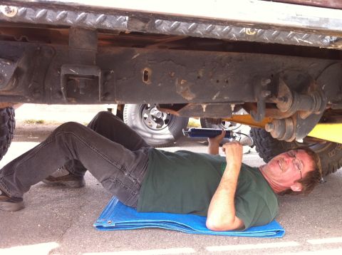 1986 Ford Bronco II - Working on the undercarriage of a vehicle. The specific model and year are not identifiable.