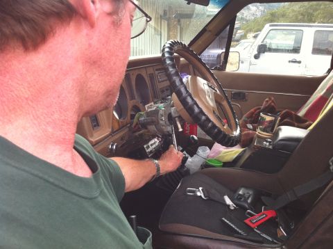 1986 Ford Bronco II - A person works on the steering column inside a vehicle, with another Jeep parked nearby.