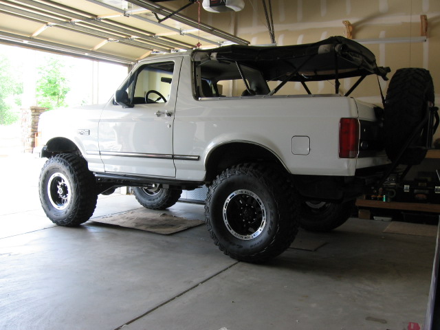 White lifted Ford Bronco SUV rear 3/4 view with soft top off, in garage