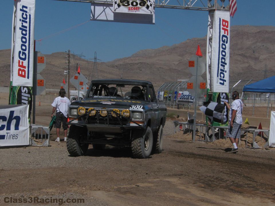 Black no. 300 race truck under a BFGoodrich start arch on a desert dirt course