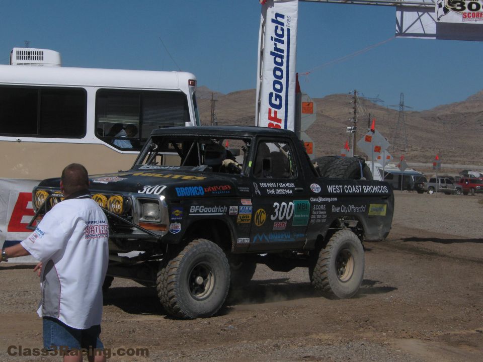 Black no. 300 West Coast Broncos race truck in a paddock with crew nearby
