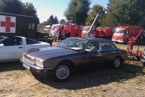 1991 Ford Crown Victoria - A modified Jaguar sedan is displayed outdoors with emergency vehicles in the background.
