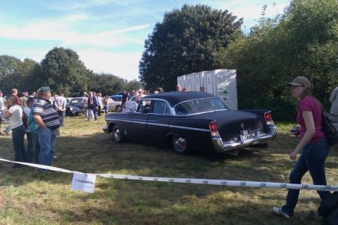 1991 Ford Crown Victoria - A 1955 Chrysler New Yorker sedan is displayed at an outdoor car show with spectators around.