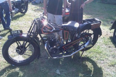 1991 Ford Crown Victoria - A classic motorcycle is displayed outdoors, with people and another vintage bike in the background.