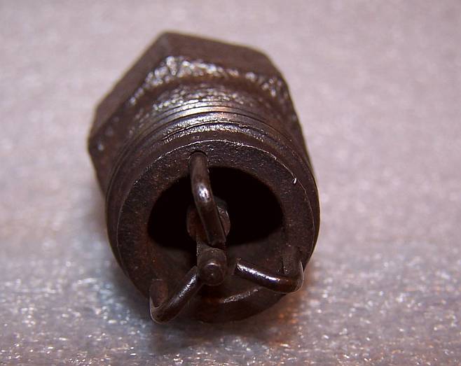 Closeup of a small rusted threaded fitting on a gray surface
