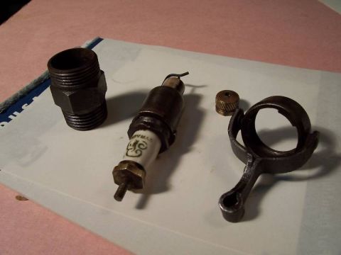 1915 Ford Model T - Close-up of a spark plug and other assorted mechanical parts laid out on a surface.