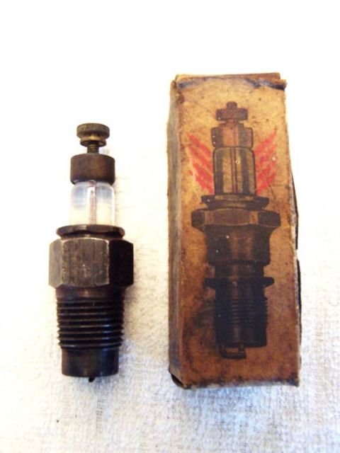 1915 Ford Model T - A vintage spark plug is displayed beside its original packaging, which features a distinctive red winged graphic.