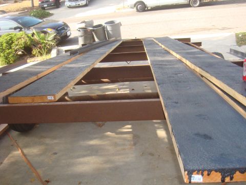 1992 Ford Bronco - A trailer is shown with wooden ramps and a tire, with other vehicles in the background.