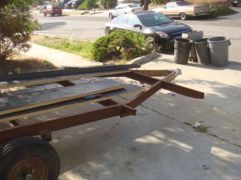 1992 Ford Bronco - A trailer frame sits on a driveway with several cars parked on the street behind it.