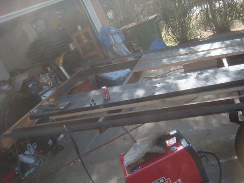1992 Ford Bronco - A partially constructed trailer frame sits in a garage, with tools and materials scattered around.