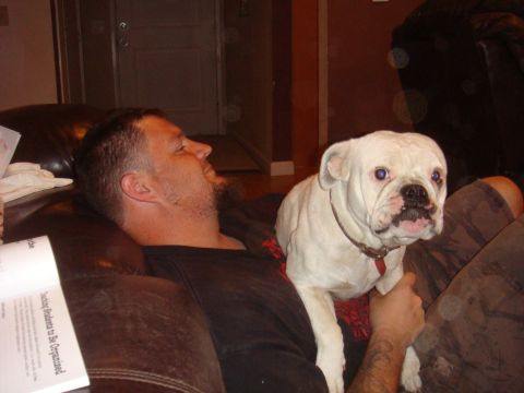 1992 Ford Bronco - A man and his white bulldog relax together on a brown leather couch, with a book visible on the left.