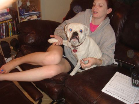 1992 Ford Bronco - A woman holds a white bulldog while sitting on a leather couch with bookshelves visible.
