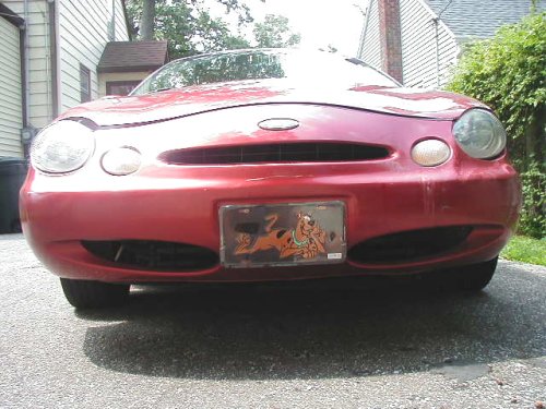 Front view of a red 1997 Ford Taurus with a Scooby-Doo license plate frame