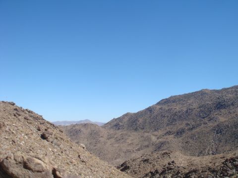 1992 Ford Bronco - A vast desert landscape stretches out under a clear blue sky, with rocky mountains dominating the view.