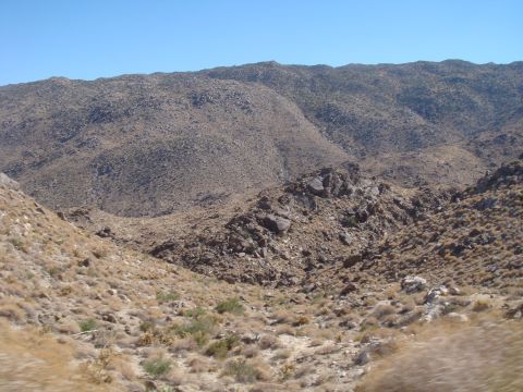 1992 Ford Bronco - A wide view of a dry, rocky desert landscape with sparse vegetation and mountains in the background.