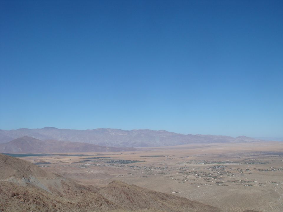 Desert landscape with mountains and a town, Supermotors logo