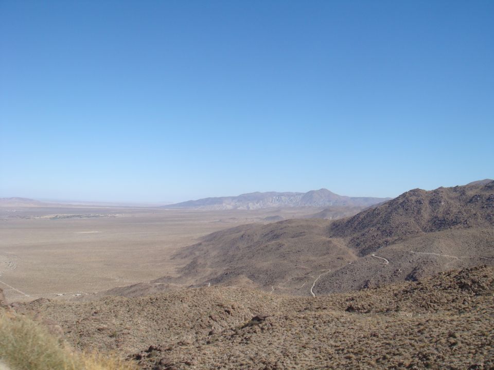 Wide shot of a dry, mountainous desert with a clear blue sky