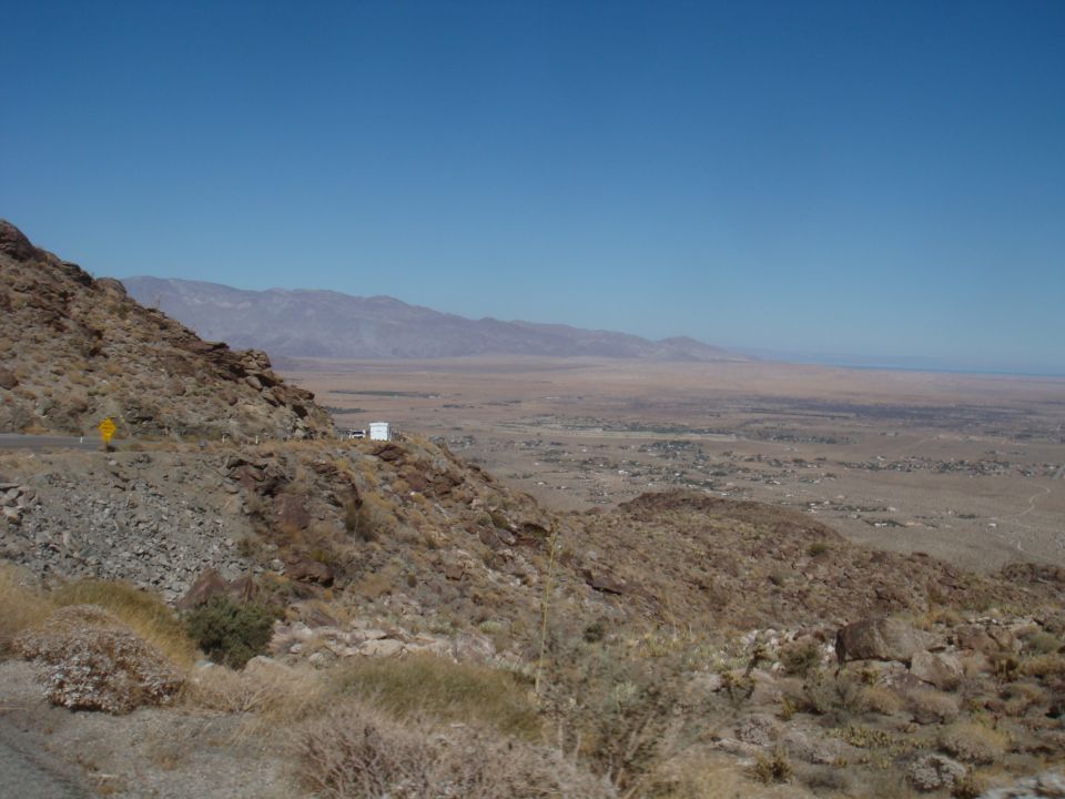 White box truck parked on a rocky mountain road overlooking a desert valley