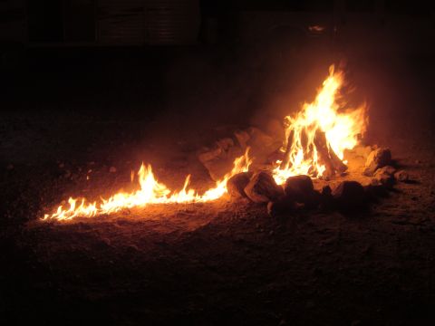 1992 Ford Bronco - A campfire burns brightly at night, surrounded by stones.