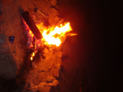 1992 Ford Bronco - A campfire burns brightly at night, illuminating the surrounding rocks and logs.