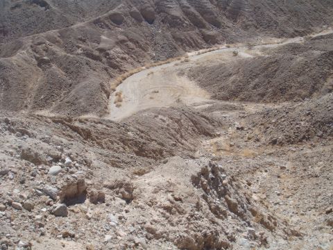 1992 Ford Bronco - A dry, rocky canyon landscape with a dirt track winding through it. A vehicle is barely visible in the distance.