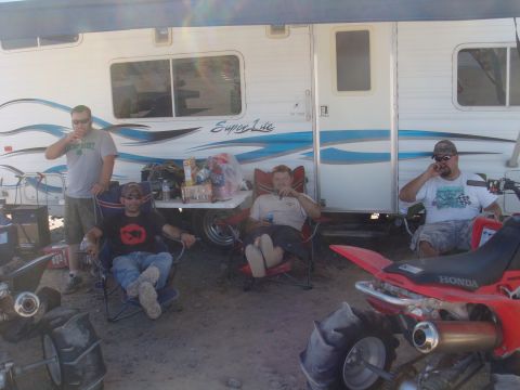 1992 Ford Bronco - A group of friends relax in lawn chairs next to a trailer, with ATVs in the foreground.