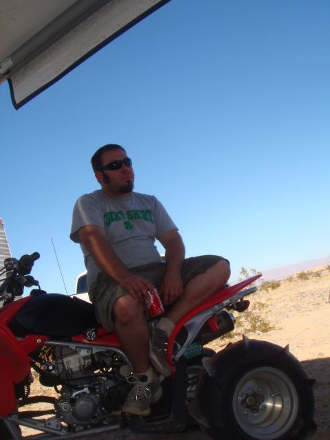 1992 Ford Bronco - A man sits on a red ATV in a desert landscape under a clear blue sky.