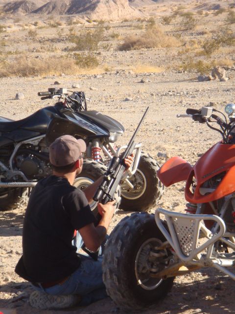 1992 Ford Bronco - Two ATVs are parked in a desert area with a person holding a rifle.