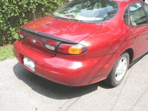 1997 Ford Taurus - Rear view of a red 1997 Ford Taurus sedan parked on asphalt.
