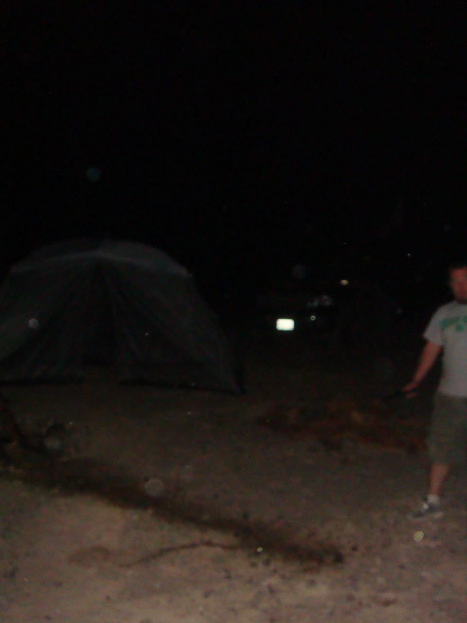 Tent and person at night with a distant vehicle light