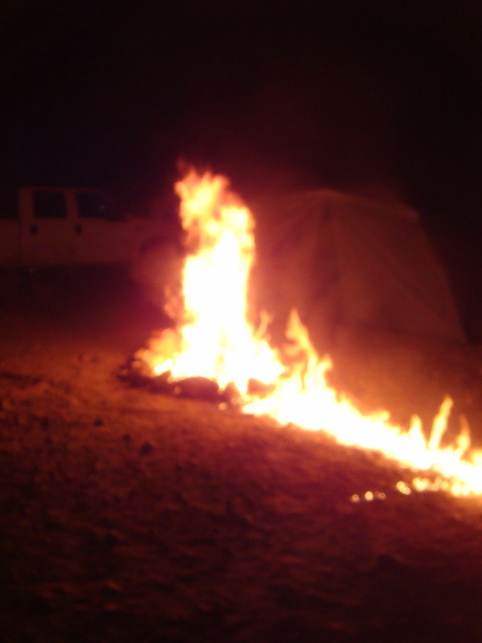 Truck parked near a large bonfire at night