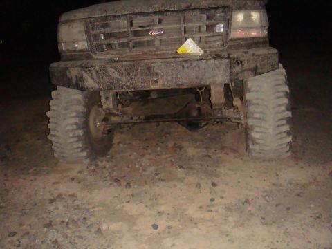 1992 Ford Bronco - This 1992 Ford Bronco is covered in mud, showing its front grille and large off-road tires.