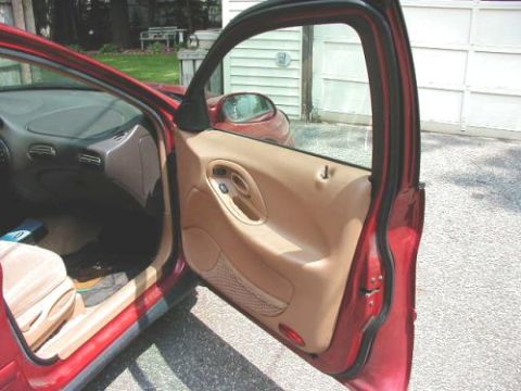 1997 Ford Taurus - The interior of a red 1997 Ford Taurus shows a tan door panel and dashboard.