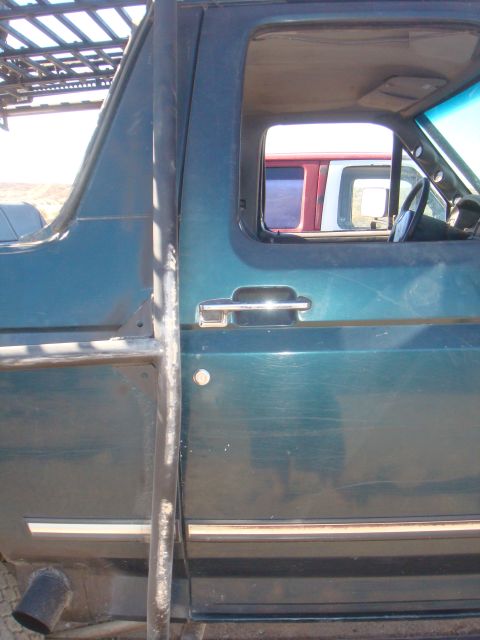 1992 Ford Bronco - The side of a green 1992 Ford Bronco is shown, a roof rack and external roll cage structure.