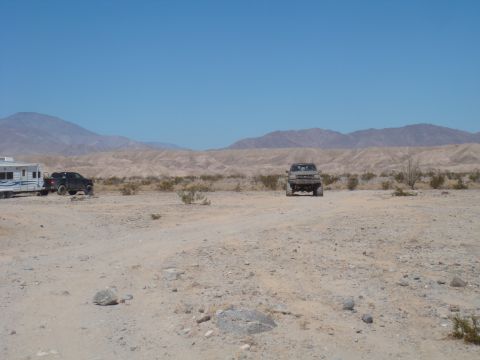 1992 Ford Bronco - Two trucks and a trailer are parked in a dry, desert landscape under a clear blue sky.