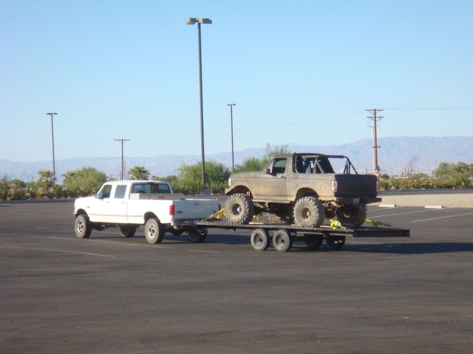 Lifted 1992 Ford Bronco on trailer, towed by white Ford F-Series truck