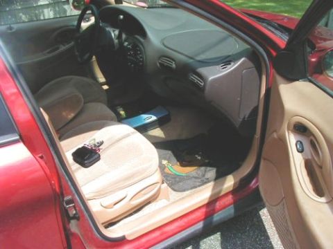 1997 Ford Taurus - The interior of a 1997 Ford Taurus shows tan cloth seats and a red exterior.