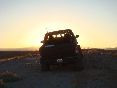1992 Ford Bronco - Black 1992 Ford Bronco parked on a dirt mound during sunset.