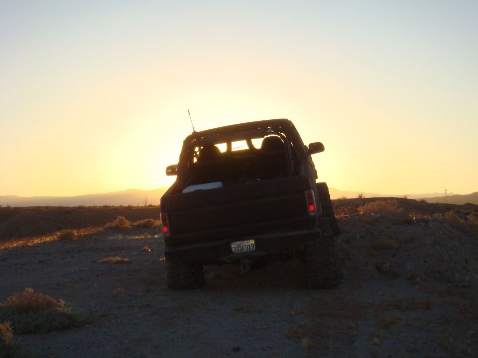 1992 Ford Bronco rear view on dirt hill with sunset
